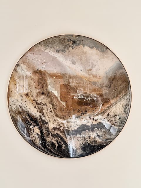 Earthbound: rond epoxywerk in aardetinten, bruin, zand en zwart, aan een witte muur