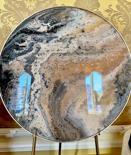 Rond werk in zwart, grijs en goud op een ezel voor goudkleurig behang